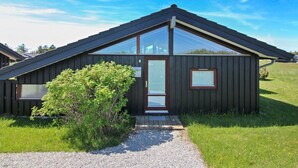 Een moderne, donker houten chalet met een schuin dak, een grote glazen deur en een klein raam.