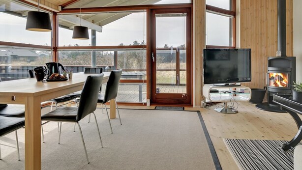 Een modern interieur met een houten eettafel, stoelen, een televisie en een houtkachel.