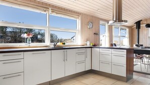 Eine moderne Küche mit weißen Schränken, einem großen Fenster und Blick ins Freie.