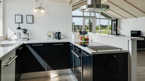 Een moderne keuken met een groot eiland, inbouwapparatuur en uitzicht op de omgeving.