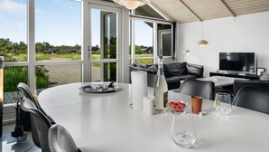 Een moderne eetruimte met een grote tafel, stoelen en een televisie.