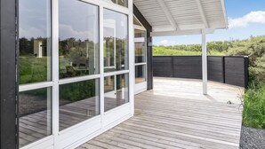 Een modern huis met grote glasramen en een houten terras.