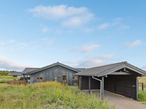 Stylish two-story building with a flat roof and covered porch, set amidst a serene natural landscape.
