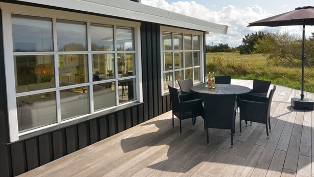 Eine moderne Außenpatio mit einem runden Tisch, Stühlen, großen Fenstern und einem Kamin.