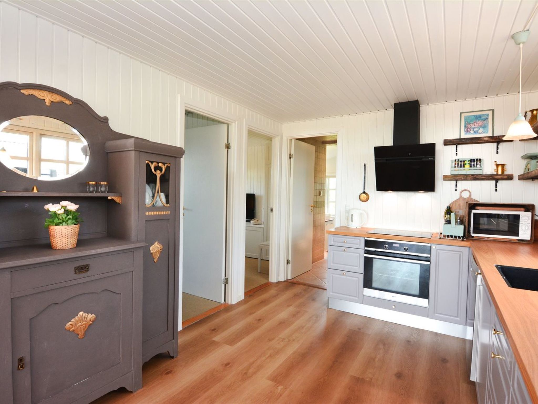 Une cuisine avec un plancher en bois, un four encastré, un four à micro-ondes et un évier.