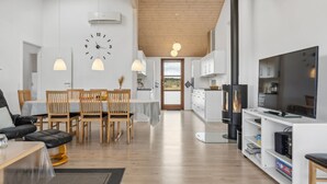 Un salon moderne comprenant un coin repas, une cuisine et un téléviseur.