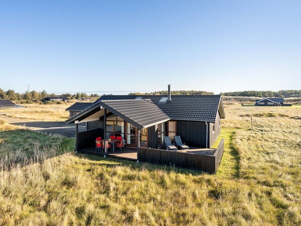 Una casa moderna con un porche cubierto, un comedor y vistas al paisaje.