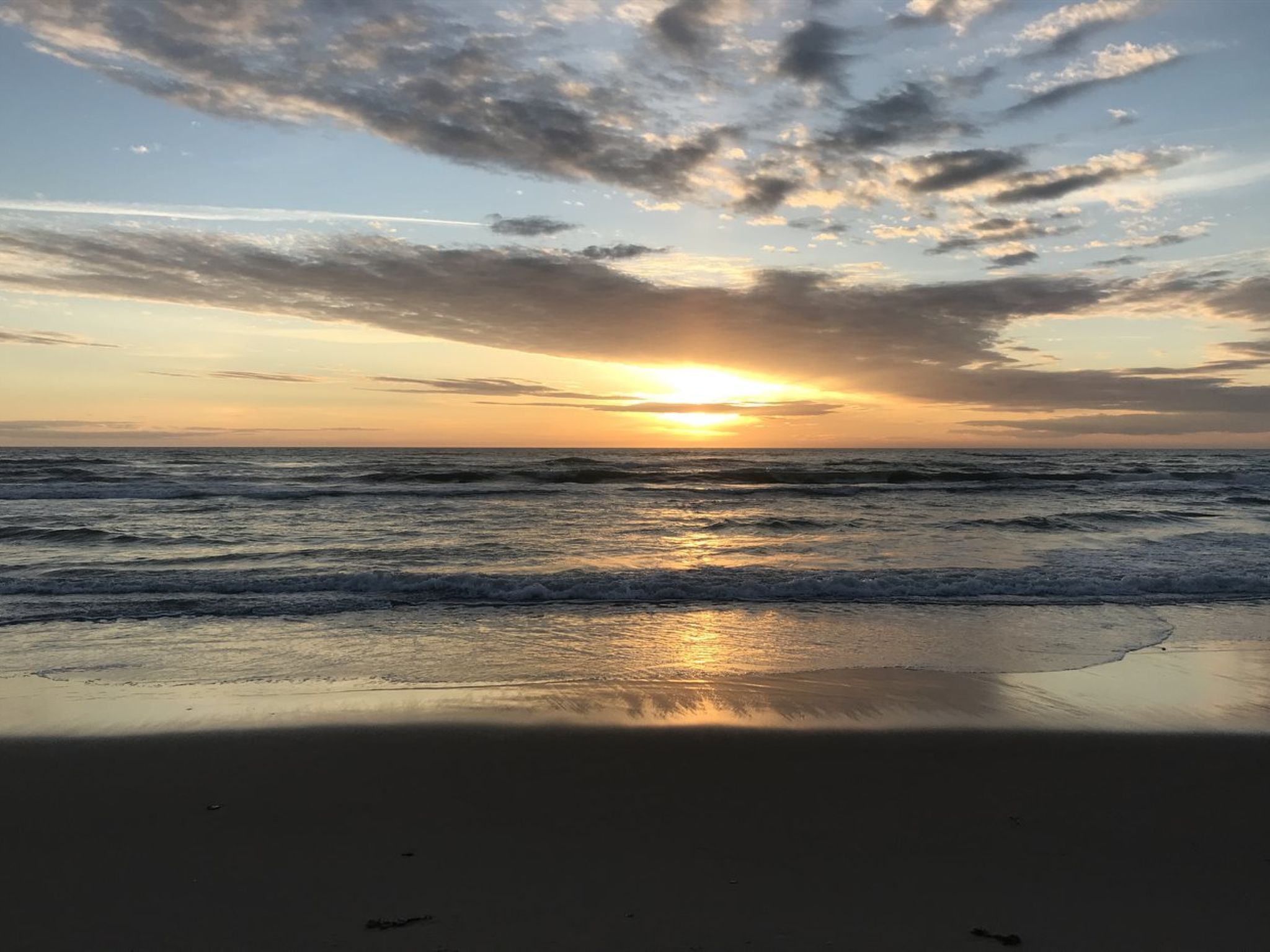 Ein Strand mit Wellen und einem Sonnenuntergang.