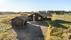 Une maison moderne avec une allée en gravier et une grande structure ressemblant à une grange.