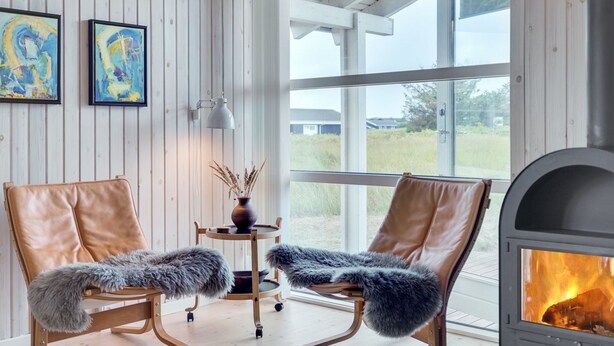 Una habitación con dos sillones de cuero, una mesita con un florero y una chimenea.