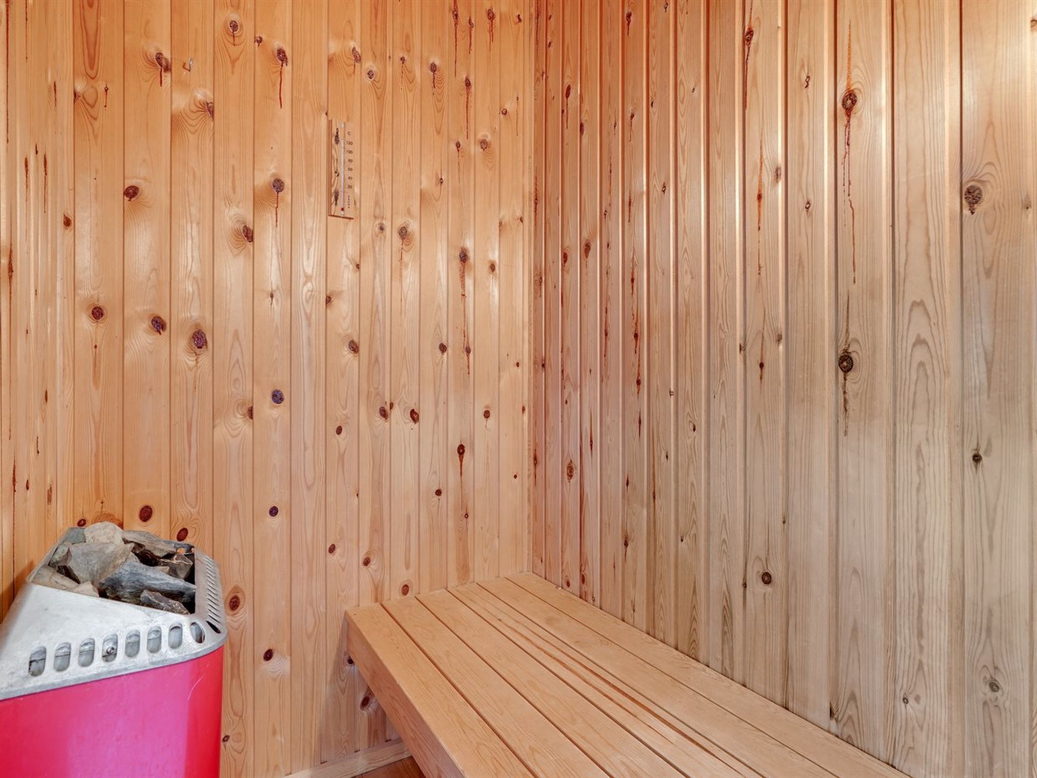 A sauna room with wooden walls and a bench.