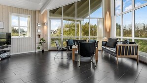 Amplia sala de estar con un ventanal grande, televisor y zona de estar con sofá y sillones.