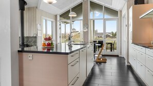 Una cocina moderna con una isla grande, armarios blancos y vistas al exterior.