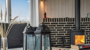 Una habitación acogedora con una chimenea de ladrillo, una mesa con velas y un cuenco de bayas rojas.