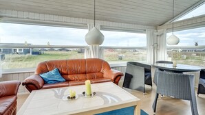 Un salon moderne avec un canapé en cuir, une table basse et des fauteuils en osier.