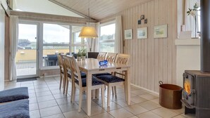 Un coin repas accueillant, avec une table et des chaises en bois, une lampe suspendue et une vue dégagée grâce à de grandes fenêtres.
