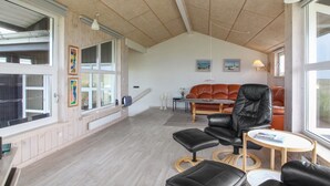 Un vaste espace de vie doté d’un haut plafond, d’un canapé en cuir, d’un fauteuil en cuir noir et d’une petite table ronde.