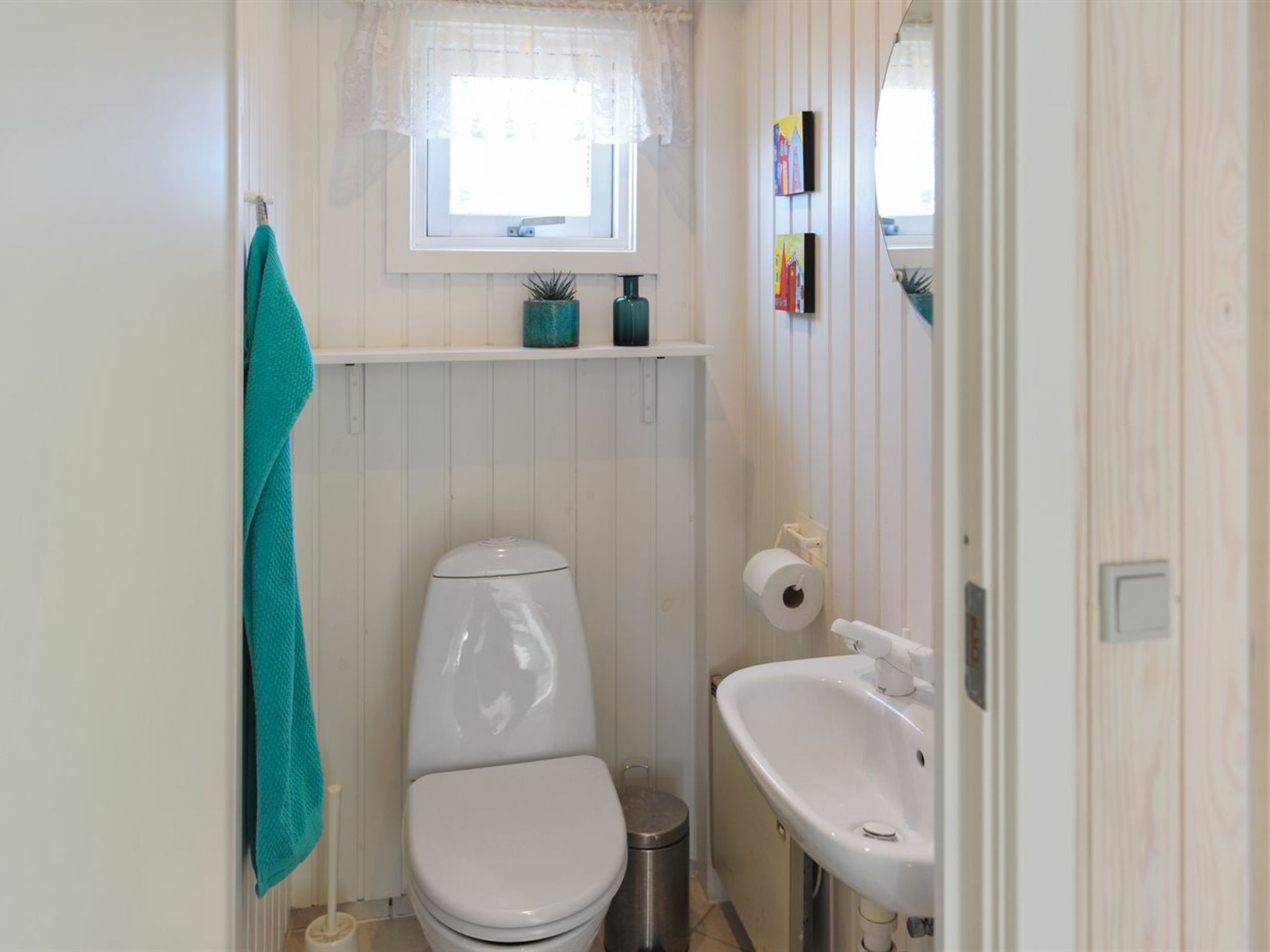 A small bathroom with a toilet, sink, and window.