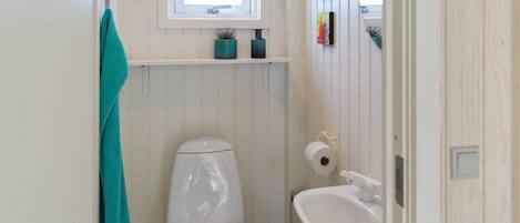 A small bathroom with a toilet, sink, and window.