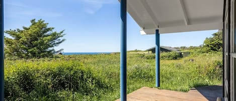 Een houten terras met uitzicht op zee en groen.