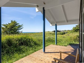 Une terrasse en bois offrant une vue sur la mer et la verdure.