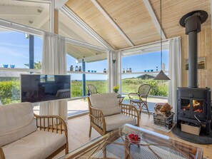 A spacious living area with a large TV, comfortable seating, a glass table, and a wood-burning stove. - "Wilma" - 400m from the sea by Interhome (Hirtshals)
