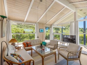 Un vaste espace de vie agrémenté d’une grande table en verre, de sièges confortables et offrant une vue sur une végétation luxuriante.