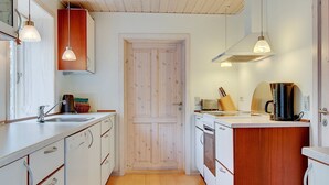 Eine kleine Küche mit Holzausstattung, einem Spülbecken, einem Herd und einer Kaffeemaschine.