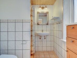 Ein Badezimmer mit einem weißen Waschbecken, einem Spiegel und einem Holzschrank.
