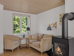 Ein gemütliches Wohnzimmer mit einer Couch, einem kleinen Tisch, einer Lampe und einem Kaminofen.