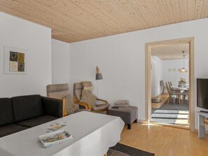 A modern living room with a sofa, armchair, and ottoman, a dining area with chairs and a table, and a TV on a stand. - "Etta" - 957m from the sea by Interhome (Hirtshals)