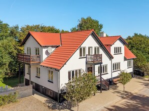Ein zweistöckiges Haus mit rotem Ziegeldach, zahlreichen Fenstern und einem Balkon.