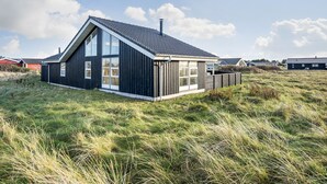 Ett modernt hus med ett sluttande tak, stora fönster och en träfasad.