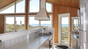 Eine moderne Küche mit großen Fenstern, Meerblick und hohen Decken.
