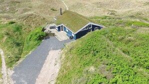 Ein Küstengebäude mit geneigtem Dach, einer Holzterrasse und einem Weg dorthin.