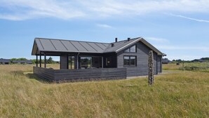 A modern house with a flat roof, large windows, and a covered porch.