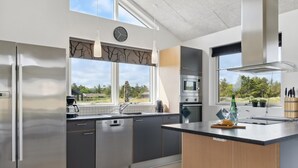 A modern kitchen with a built-in dishwasher, stainless steel appliances, and a large window offering a view of the outdoors.