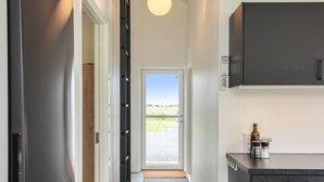 A modern kitchen with a refrigerator, a coffee maker, and a bottle on the counter.