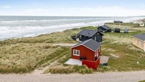 Una proprietà costiera con diverse cabine, un edificio rosso e vista sulla spiaggia.