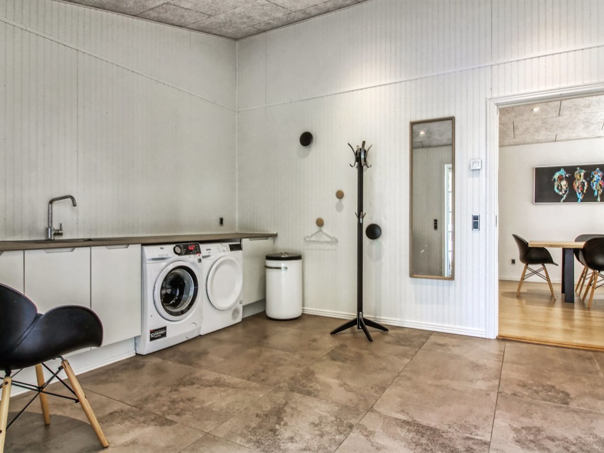 Eine moderne Küche mit Waschmaschine, Spüle und Essbereich mit Stühlen.