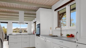 A modern kitchen with white cabinets, a stainless steel sink, and a window with a view of the outside.