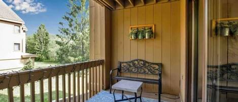 A balcony with a wooden railing, a bench, and a small table.