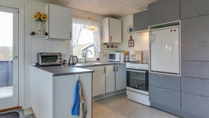Una cucina compatta con mobili bianchi e grigi, forno integrato, microonde e tostapane.