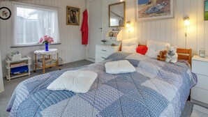 Una camera da letto accogliente con un letto grande, un comodino, una cassettiera, una finestra con tende e un quadro al muro.