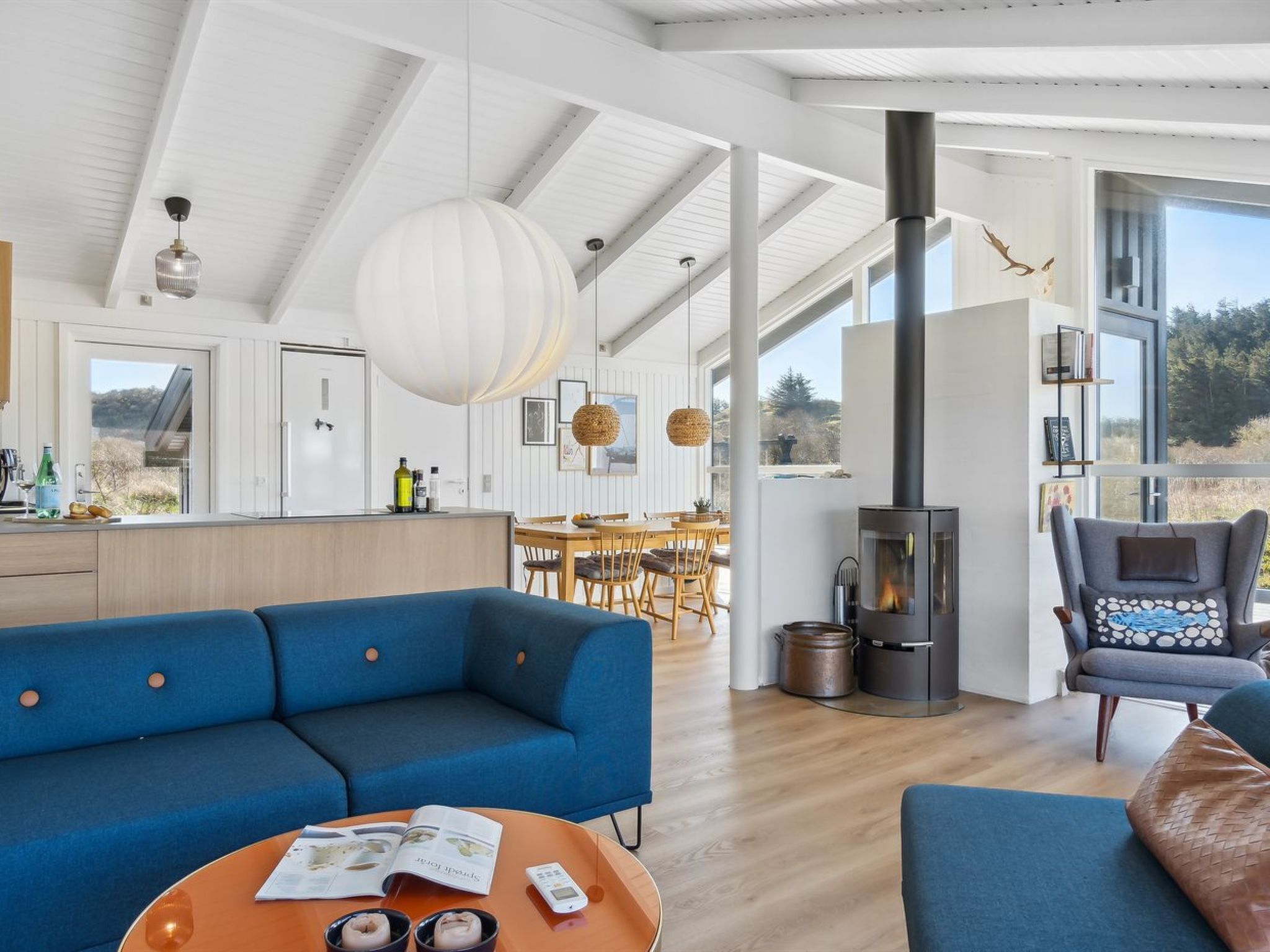 Una sala moderna con un sofá azul, una mesa de centro redonda y una chimenea.