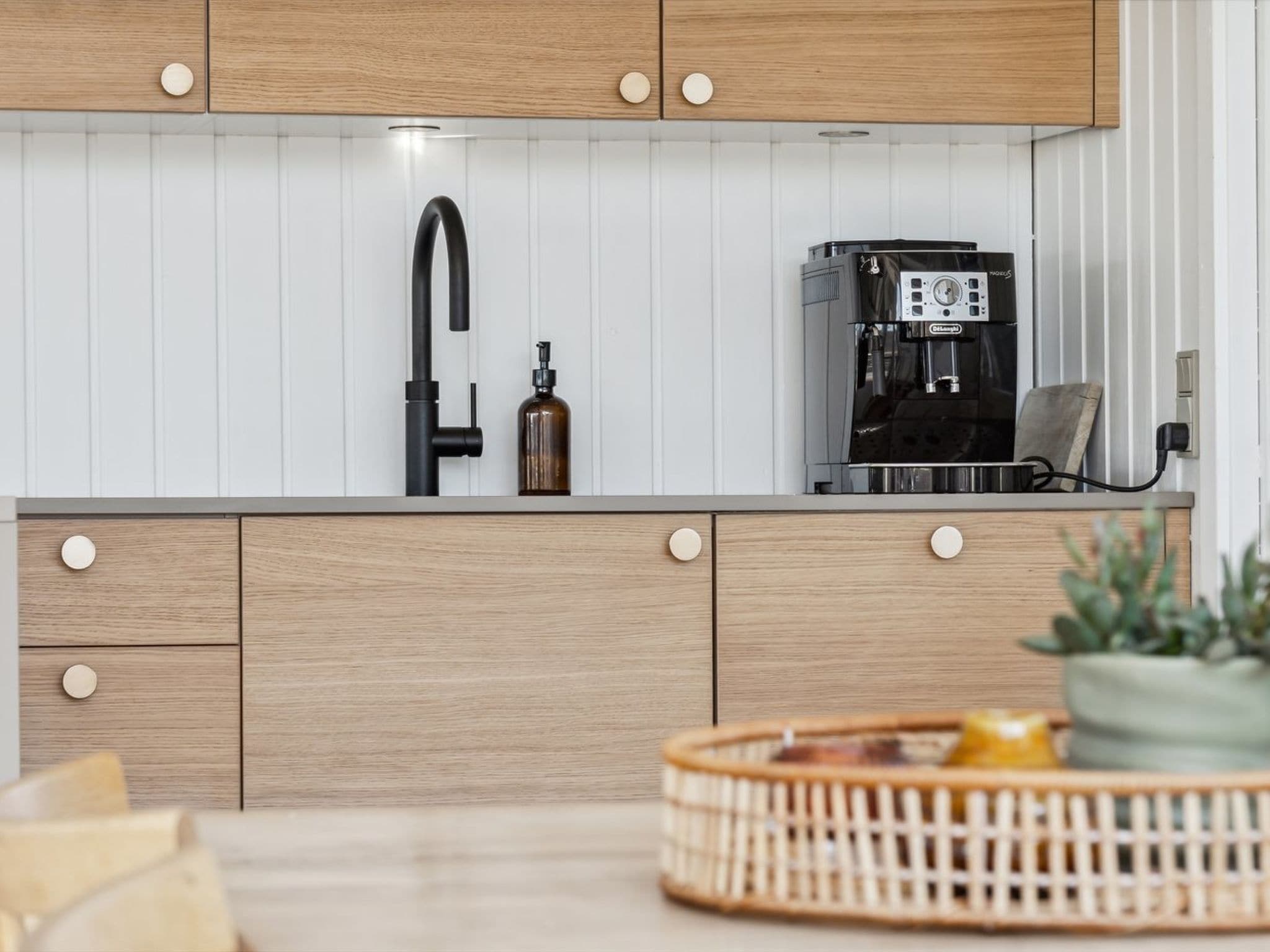 Una cocina moderna con armarios de madera, un grifo negro y una cafetera.