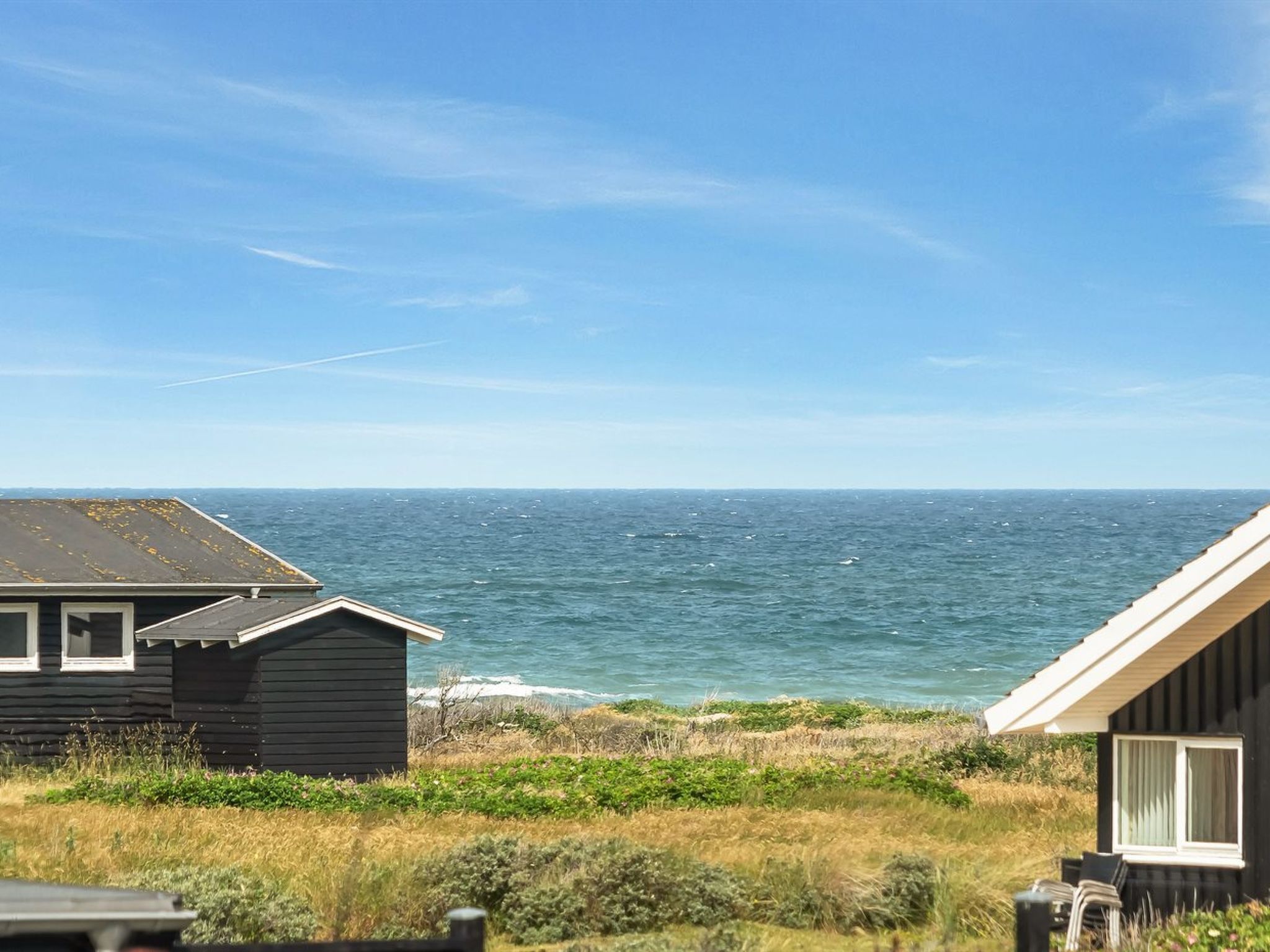 Une vue sur la côte, avec un petit bâtiment et une construction plus imposante, tous deux dotés de fenêtres bien visibles et offrant une vue dégagée sur la mer.