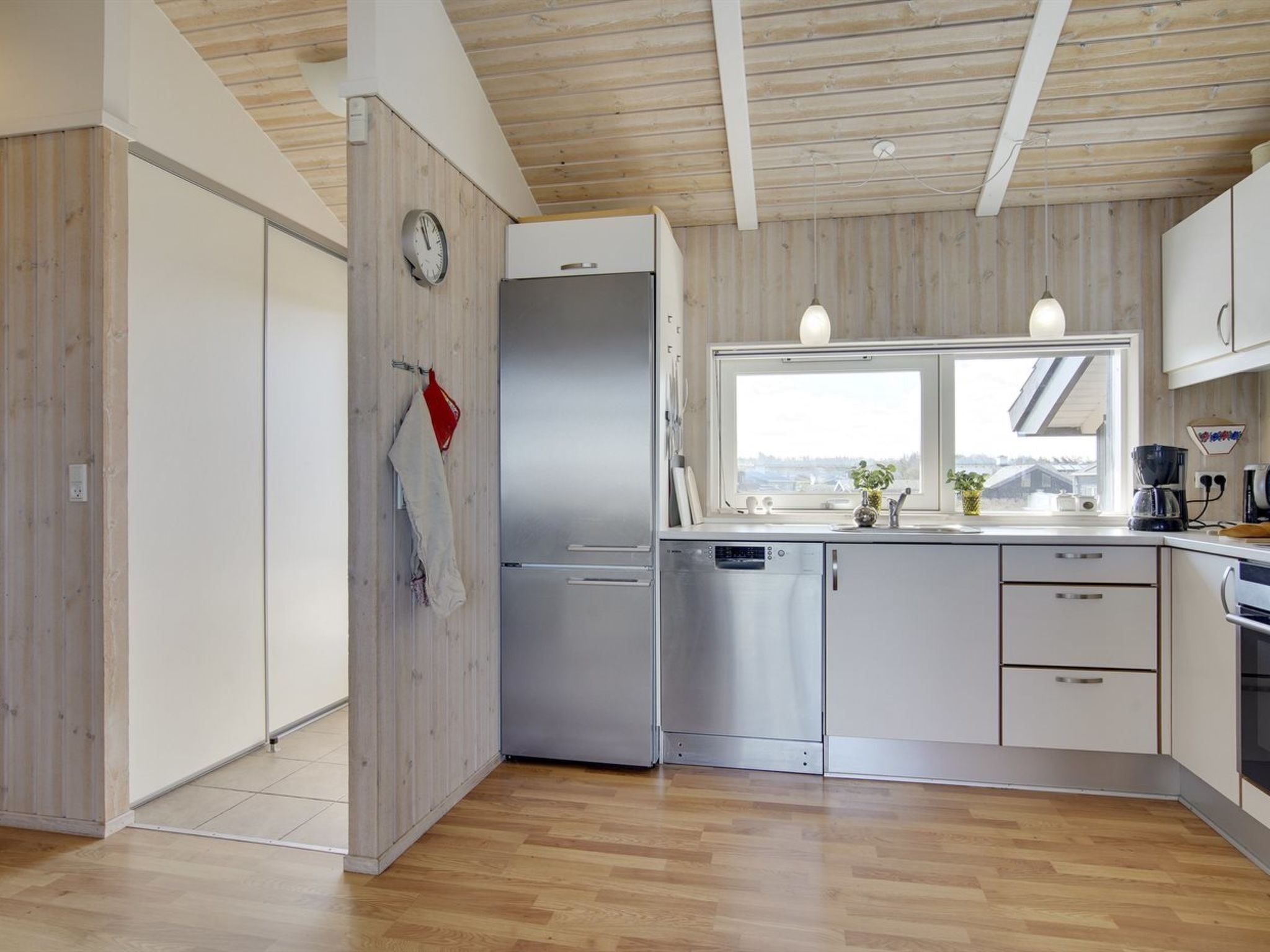 Een moderne keuken met houten lambrisering, roestvrijstalen apparatuur en een raam met uitzicht.