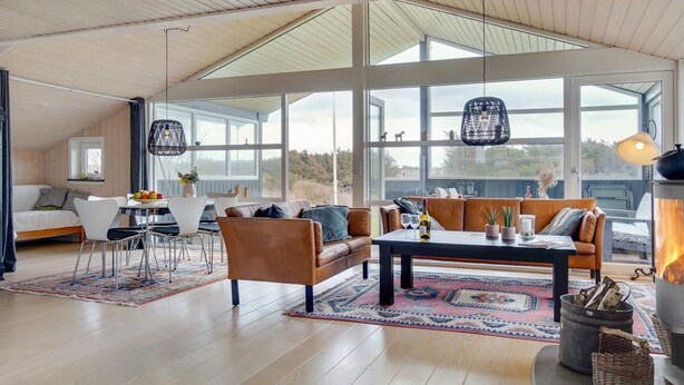 Een ruime woonkamer met een hoge plafond, grote ramen, een gezellige zithoek en een open haard.