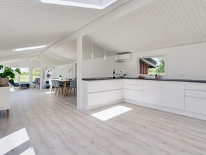 A modern kitchen with white cabinetry, a dining area with chairs, and a large window providing natural light.